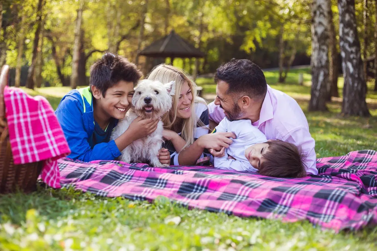 A family laying on the ground with their dog.